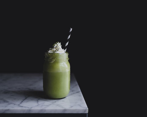 Nahaufnahme von Matcha-Shake in der Flasche auf Marmor Zähler gegen schwarzen Hintergrund, lizenzfreies Stockfoto