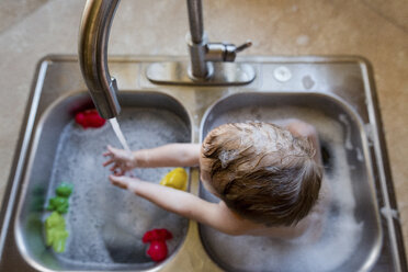 Hoher Blickwinkel eines Jungen, der mit Wasser im Waschbecken spielt - CAVF24457