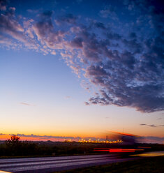 Light trails on road against cloudy sky during sunset - CAVF24496