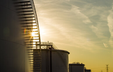 Niedriger Blickwinkel auf Lagertanks in einer Ölraffinerie gegen den Himmel bei Sonnenuntergang - CAVF24529