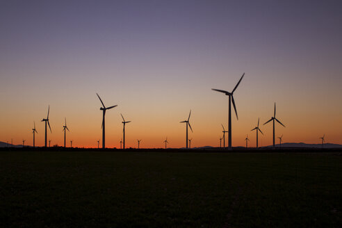 Silhouette wind turbines on field against clear sky during sunset - CAVF24541