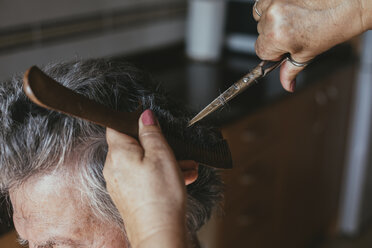 Abgeschnittene Hände einer Friseurin, die einem männlichen Kunden die Haare schneidet - CAVF24547