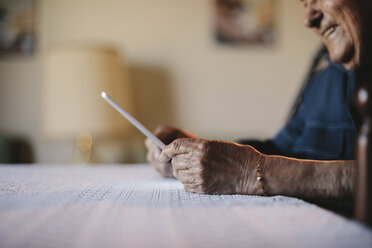 Ausgeschnittenes Bild eines älteren Mannes, der einen Tablet-Computer am Tisch hält - CAVF24552