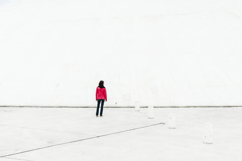 Rückansicht einer Frau, die auf einer Straße vor einer weißen Wand steht - CAVF24556