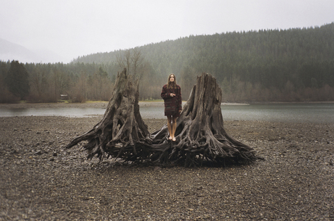 Woman standing on driftwood shore by Rattlesnake Lake stock photo