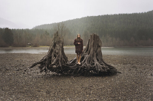 Woman standing on driftwood shore by Rattlesnake Lake - CAVF24585