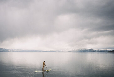 Frau Paddleboarding auf See gegen bewölkten Himmel - CAVF24600