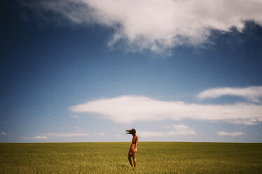 Frau stehend auf grasbewachsenem Feld gegen den Himmel - CAVF24612