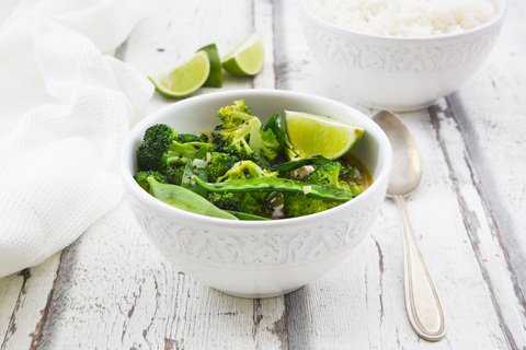 Green thai curry with broccoli, pak choi, snow peas, baby spinach, lime and rice stock photo