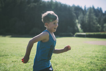 Side view of happy boy running with ball at park - CAVF24665