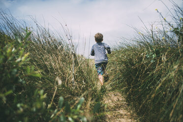 Rear view of boy running on field amidst plants at A_o Nuevo State Park - CAVF24679