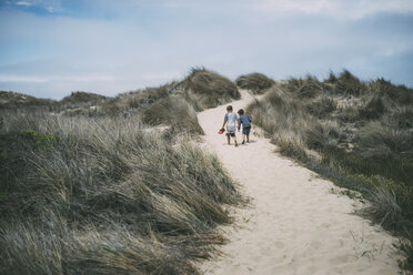 Rear view of brothers walking on desert amidst plants at A_o Nuevo State Park - CAVF24680