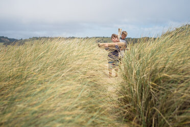 Brothers carrying firewood at grassy field against sky at A_o Nuevo State Park - CAVF24681