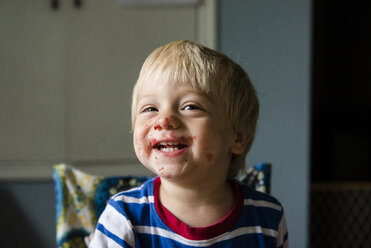 Cheerful boy with messy face sitting at home - CAVF24721