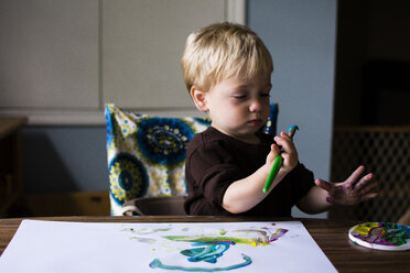 Niedlicher Junge, der zu Hause sitzt und auf Papier zeichnet - CAVF24729