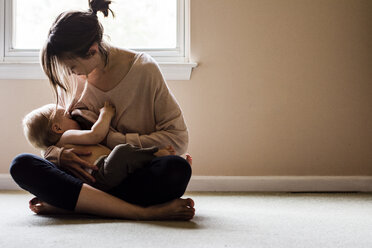Woman breastfeeding son while sitting at home - CAVF24732
