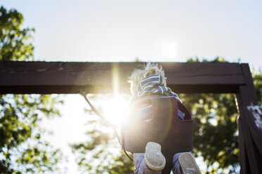 Niedriger Blickwinkel des Jungen Schaukeln auf dem Spielplatz an einem sonnigen Tag - CAVF24765