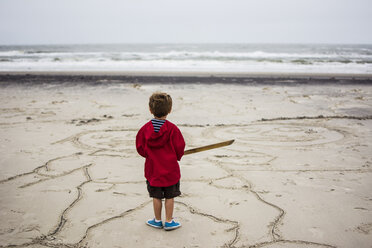 Rückansicht eines Jungen, der auf dem Sand am Strand steht - CAVF24777