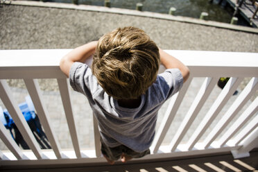 Hoher Blickwinkel des Jungen, der an einem sonnigen Tag am Geländer steht - CAVF24783