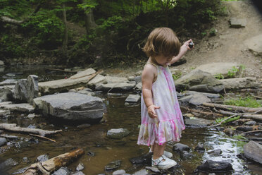 Side view of girl standing on rocks in stream - CAVF24820