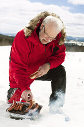 Mann kocht Hot-Dogs im Schnee - FOLF00001