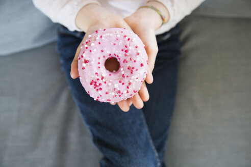 Mädchenhand hält rosa Krapfen, Nahaufnahme - LVF06819