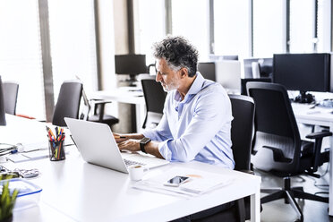 Älterer Geschäftsmann arbeitet am Schreibtisch im Büro - HAPF02664