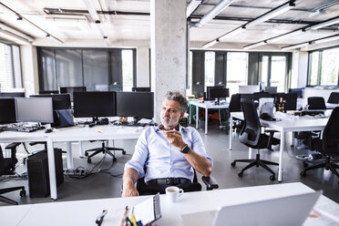 Mature businessman sitting at desk in office using smartphone - HAPF02675