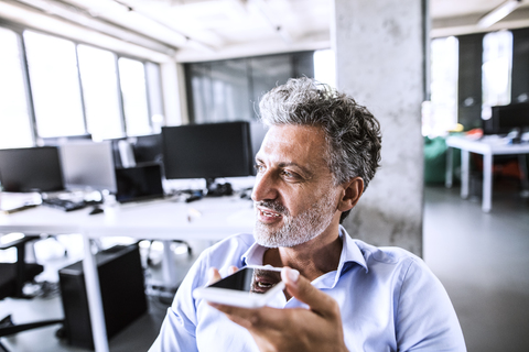 Portrait of mature businessman using smartphone in office stock photo