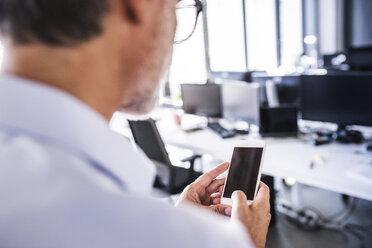 Nahaufnahme eines Geschäftsmannes im Büro, der ein Smartphone benutzt - HAPF02689