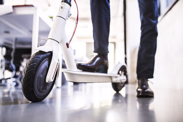 Nahaufnahme eines Geschäftsmannes mit Motorroller im Büro - HAPF02707