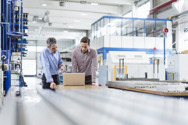 Businessmen using laptop in production hall - DIGF03484