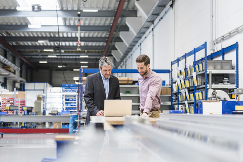 Geschäftsleute mit Laptop in der Produktionshalle, lizenzfreies Stockfoto