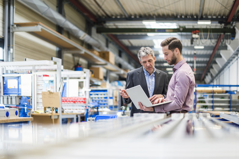 Geschäftsleute mit Laptop in der Produktionshalle, lizenzfreies Stockfoto