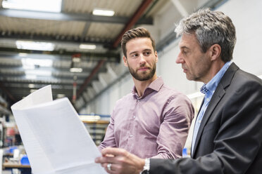 Geschäftsleute mit Plan bei der Besprechung in der Produktionshalle - DIGF03497