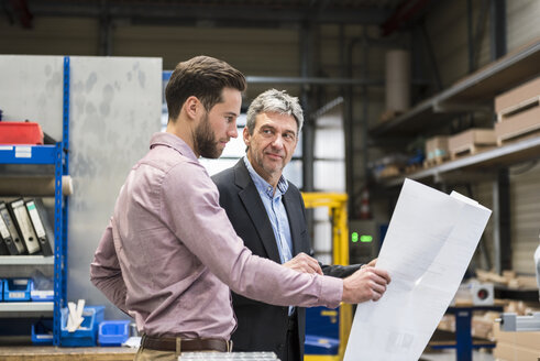 Geschäftsleute mit Plan bei der Besprechung in der Produktionshalle - DIGF03498