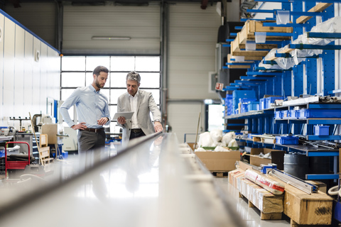 Businessmen using tablet during meeting in production hall stock photo