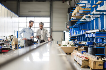 Businessmen using tablet during meeting in production hall - DIGF03504