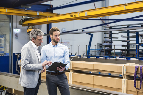 Businessmen during meeting with clipboard in production hall stock photo