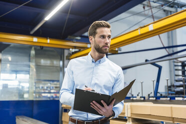 Young businessman with clipboard in production hall - DIGF03513