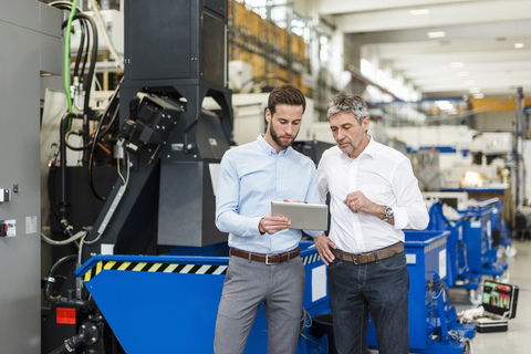 Businessmen using tablet during meeting in production hall stock photo