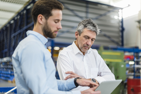 Businessmen using tablet during meeting in production hall stock photo