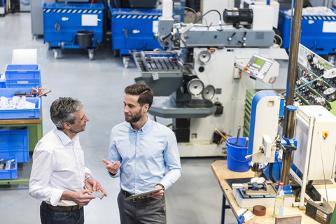 Businessmen using tablet during meeting in production hall stock photo