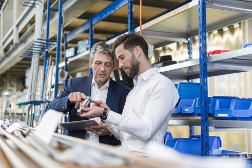 Geschäftsleute bei der Besprechung mit Tablet und Produkt in der Produktionshalle - DIGF03523