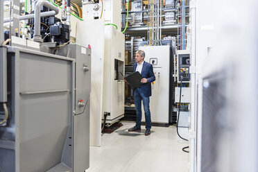 Businessman with folder in production hall - DIGF03526