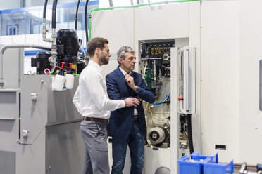 Businessmen looking at machine in factory - DIGF03527