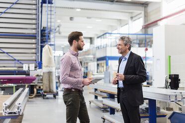 Businessmen using tablet during meeting in production hall - DIGF03540