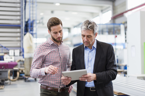 Businessmen using tablet during meeting in production hall stock photo