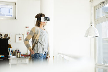 Woman wearing VR glasses at home - MOEF00925