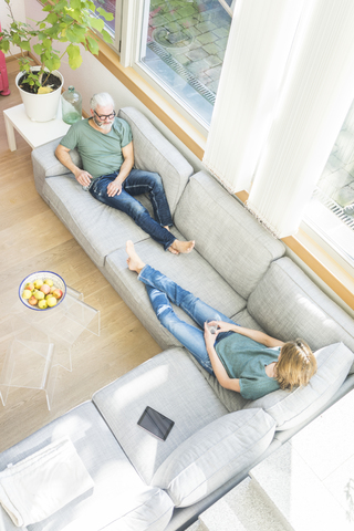 Älteres Paar entspannt sich auf der Couch zu Hause, lizenzfreies Stockfoto